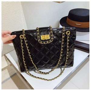 Detail of black quilted leather tote bag featuring gold chain straps and twist lock