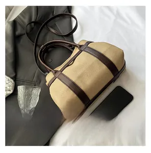 Detail of canvas and leather stitching on a retro khaki tote bag with brown trim