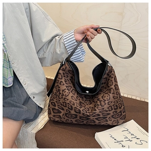 Dettaglio della texture scamosciata leopardata e della tracolla in pelle nera della borsa