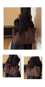 Detailed view of coffee suede tote bag showing stitching and side metal buckle texture