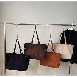 Selection of large suede tote bags in black, coffee, caramel and cream hanging on hooks