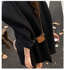 Detail of brown suede mini neck bag on model with autumnal urban background scenery