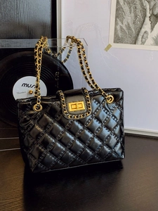 Classic black quilted tote bag with golden chain strap and rhombus pattern in lifestyle setting
