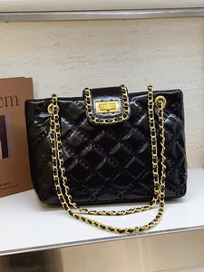 Glossy black quilted tote bag with golden chain strap and metallic lock closure