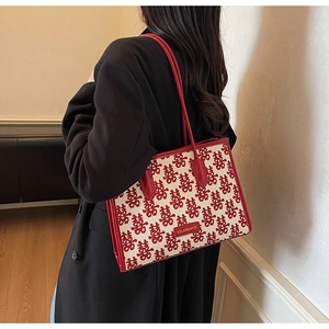 Detail view of red Double Happiness jacquard tote bag with leather straps on a model
