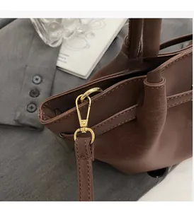 Détail du fermoir mousqueton doré brillant et texture cuir d'un sac à main marron
