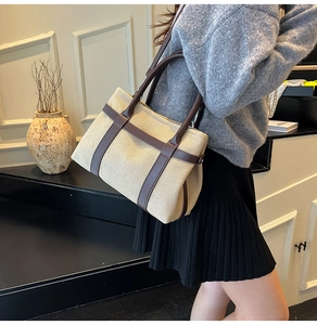 Chic beige canvas tote bag with brown leather straps shown worn by model in soft lighting