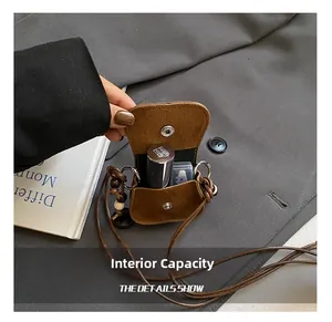 Detail showing interior capacity of a brown suede mini crossbody bag for lipstick