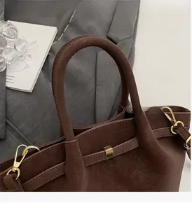 Détail d'un cabas en cuir marron foncé avec poignées solides et finitions dorées