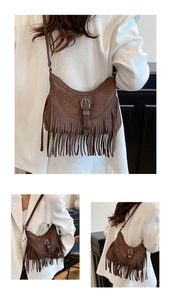 Detail of a brown suede hobo bag with fringe tassels and vintage engraved metal buckle