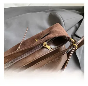 Detail of chocolate brown tote showing suede patchwork and golden metal hardware