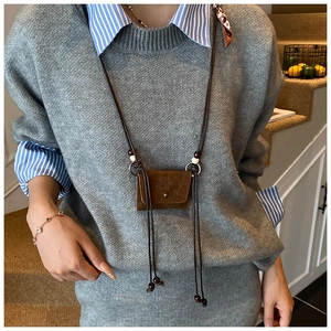 Detail of a brown suede mini neck pouch on a grey knit sweater with wood bead accent