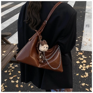 Dettaglio borsa a spalla marrone vintage con catena d'argento e charm orsetto peluche