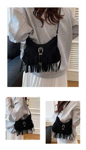 Detail view of black fringe crossbody bag with western silver buckle and tassel accents