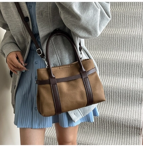 Detail of a brown canvas tote bag featuring adjustable shoulder straps and top handles