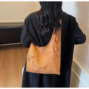 Detail of soft brown suede tote bag with knot decoration and silver metal ring buckle