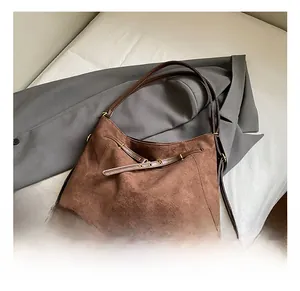 Detail view of brown suede tote bag with leather straps and gold buckle for autumn style