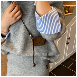 Detail of a brown suede mini neck pouch with long strap and small beads on grey sweater