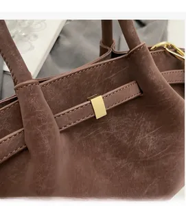 Détail d'un sac à main marron vintage avec une boucle métallique carrée dorée