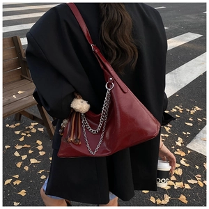 Dettaglio borsa sottobraccio in pelle lucida bordeaux con catena d'argento e orsetto