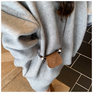 Close-up of brown suede mini crossbody bag with bead accents on gray knit sweater