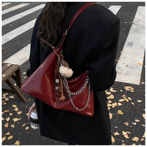 Dettaglio della borsa hobo in pelle bordeaux con catene, nappa e ciondolo a orsetto