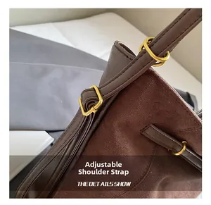 Detail of adjustable shoulder strap with gold-tone hardware on brown suede tote bag