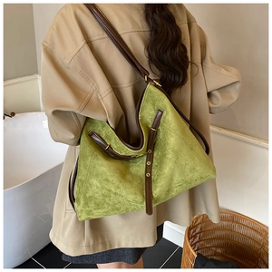 Detail of green suede tote bag featuring brown leather straps and vintage gold hardware