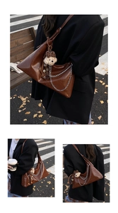 Dettaglio borsa sottospalla vintage in pelle marrone con catena e ciondolo a forma di orso