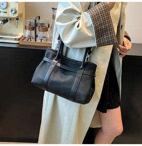 Close-up of black pebble leather tote bag with decorative straps and metal hardware