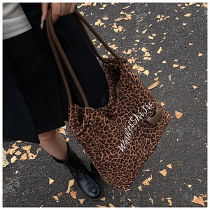 Leopard print tote bag with white embroidery on a street background with autumn leaves