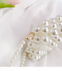 Detail of white faux pearl woven mini bag featuring premium gold metal lobster clasp hook