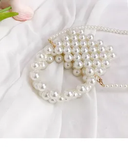 Detail of white handmade pearl mini bag with dual woven handle and long shoulder chain