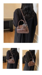 Détail du sac Boston marron foncé avec nœud décoratif et pendentif à carreaux