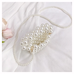 Detail of cream white pearl woven mini bag with gold lobster clasp and long strap