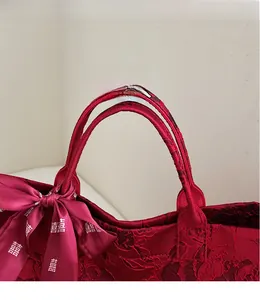 Detail einer roten Jacquard-Tasche mit Blumenmuster und festlicher Xi-Schleife am Griff