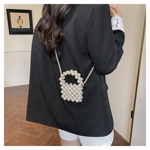 Chic mini pearl woven handbag with shoulder strap styled on a black blazer
