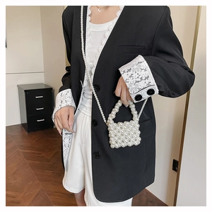 Detailed view of hand-woven white pearl mini bag with elegant pearl strap on black blazer