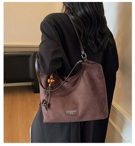 Détail du sac cabas en daim café noir avec étiquette mode et breloque à pompon décorative