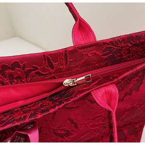 Detail der roten Jacquard-Tasche mit floraler Textur und goldenem Metallreißverschluss