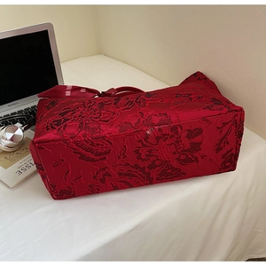 Detail der roten Jacquard-Einkaufstasche mit Blumenmuster und Schleife auf dem Tisch
