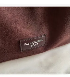 Gros plan sur la texture en daim marron foncé et l'étiquette de marque sur le sac fourre-tout