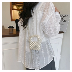 Detailed back view of a mini white pearl woven bag with round handle and shoulder chain