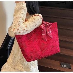 Detailansicht rote Tote Bag mit 3D-Blumenspitze und Satinschleife mit Glückssymbolen