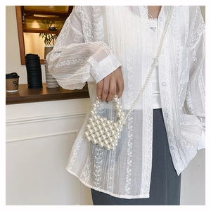 Close-up of handmade white pearl woven mini bag with delicate beaded chain and handle
