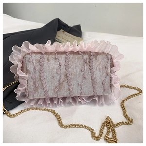 Detailed view of a pink velvet chain bag with ruffle trim on a stylish background