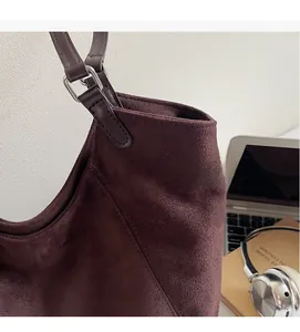 Détail de la couture d'un sac en daim avec boucle argentée dans un décor de bureau