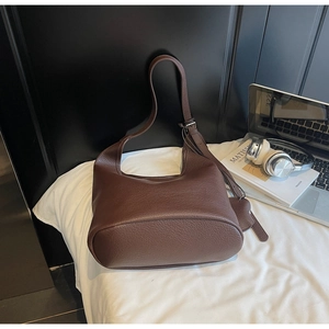 Detailed view of dark brown pebbled leather texture and adjustable strap on a bucket bag