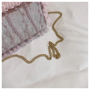 Close-up of light purple floral fabric with lace trim and gold chain on the handbag