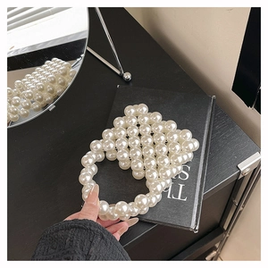 Detailed close-up of white oversized pearl beaded mini bag on a black decorative book